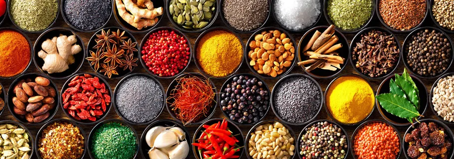 Assorted whole spices in bowls — star anise, cloves, cardamom, peppercorns, cinnamon and dried chilli